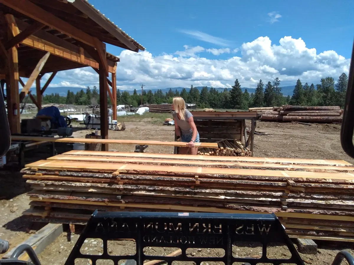 Sawmill worker handling fresh-cut lumber at the mill